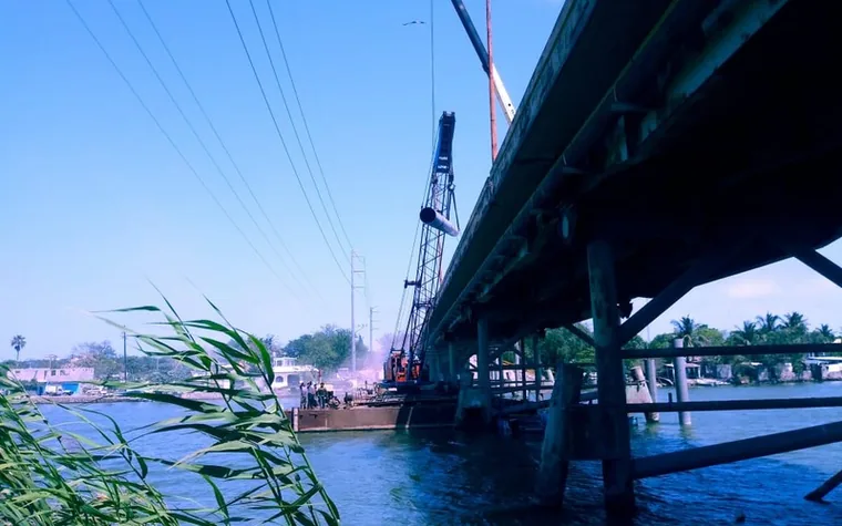 Grúa trabajando bajo un puente sobre el río